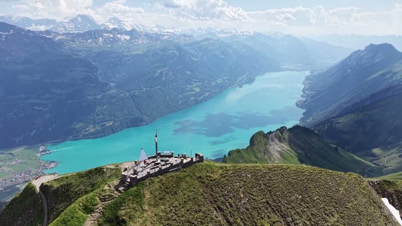 Luftaufnahme des türkisfarbenen Brienzersees mit Aussichtsplattform auf einem Grat